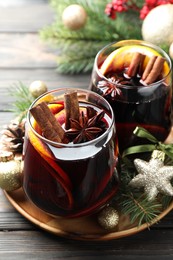 Photo of Tasty mulled wine with spices and Christmas decor on wooden table, closeup