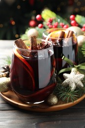 Photo of Tasty mulled wine with spices and Christmas decor on wooden table, closeup