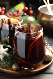 Photo of Tasty mulled wine with spices and Christmas decor on wooden table, closeup