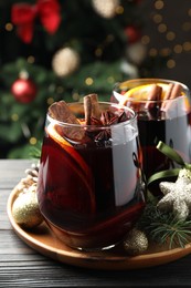 Photo of Tasty mulled wine with spices and Christmas decor on wooden table, closeup