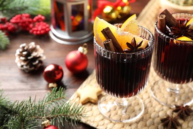 Photo of Tasty mulled wine with spices and Christmas decor on wooden table, closeup