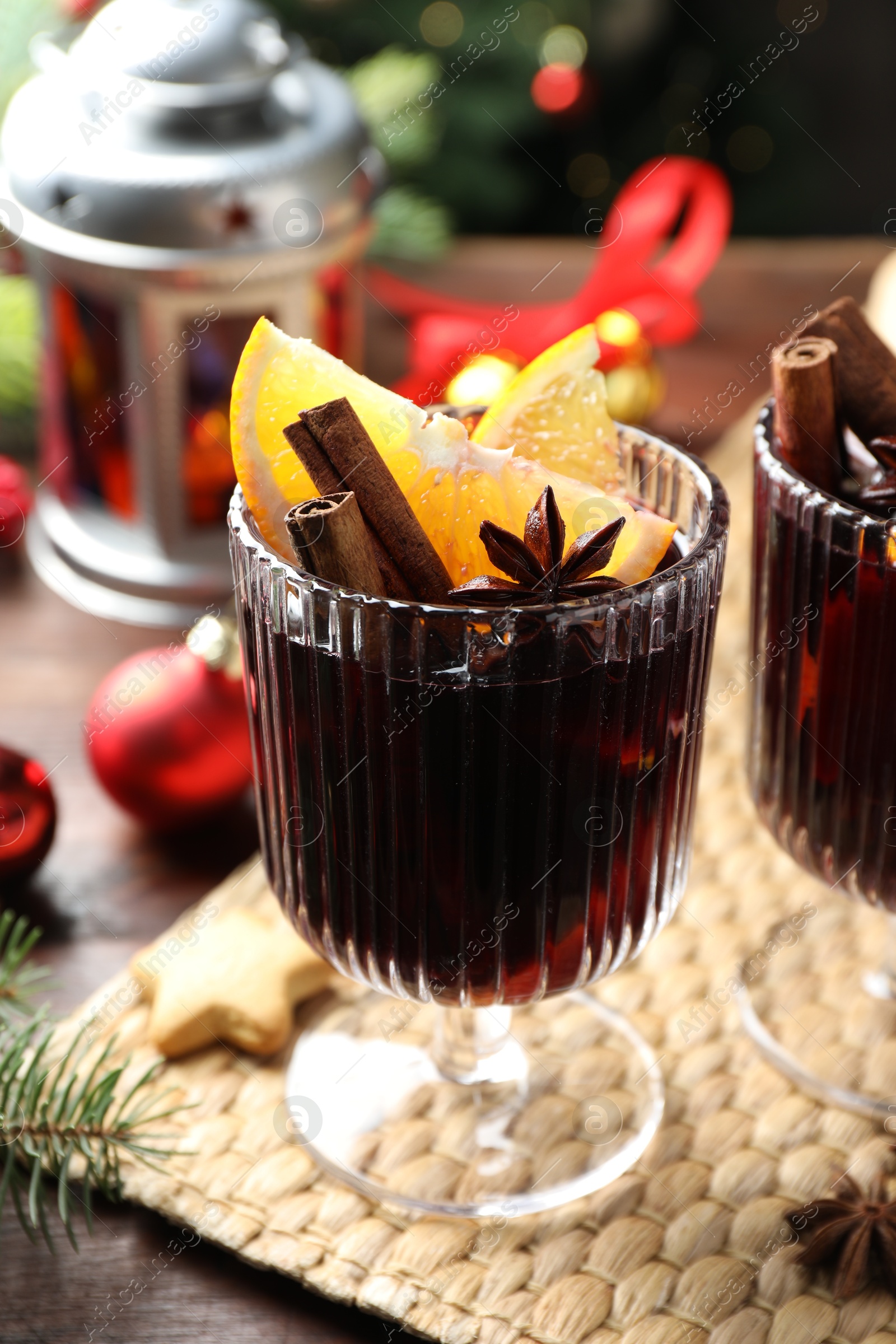 Photo of Tasty mulled wine with spices and Christmas decor on table, closeup