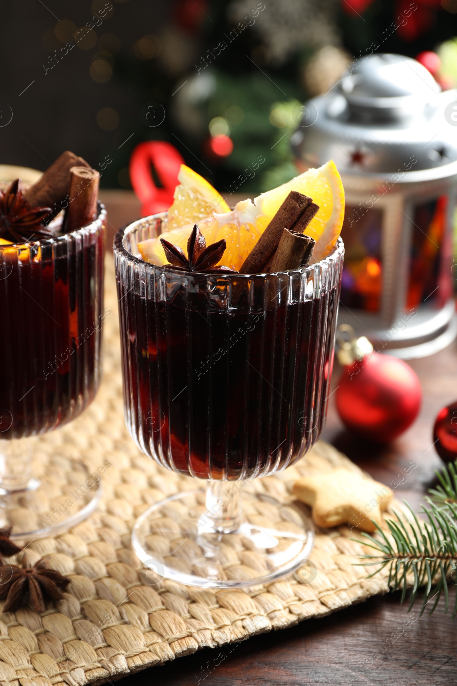 Photo of Tasty mulled wine with spices and Christmas decor on wooden table, closeup