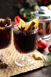 Photo of Tasty mulled wine with spices and Christmas decor on wooden table, closeup