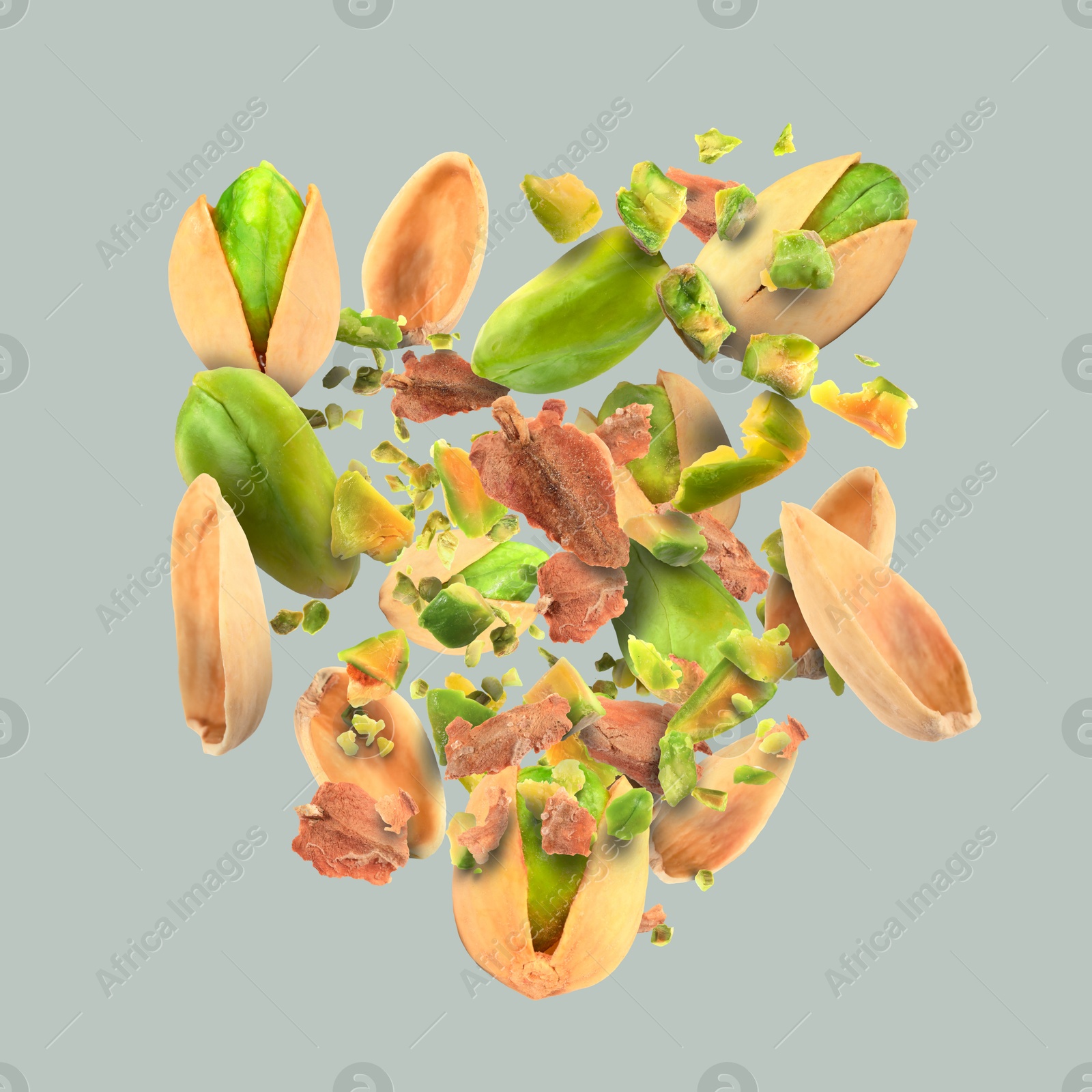 Image of Tasty pistachios with cracked nutshell in air on light grey background