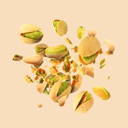 Image of Tasty pistachios with cracked nutshell in air on dark beige background