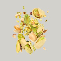 Image of Tasty pistachios with cracked nutshell in air on light grey background