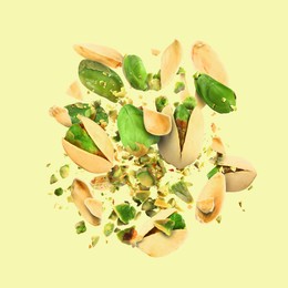 Image of Tasty pistachios with cracked nutshell in air on color background