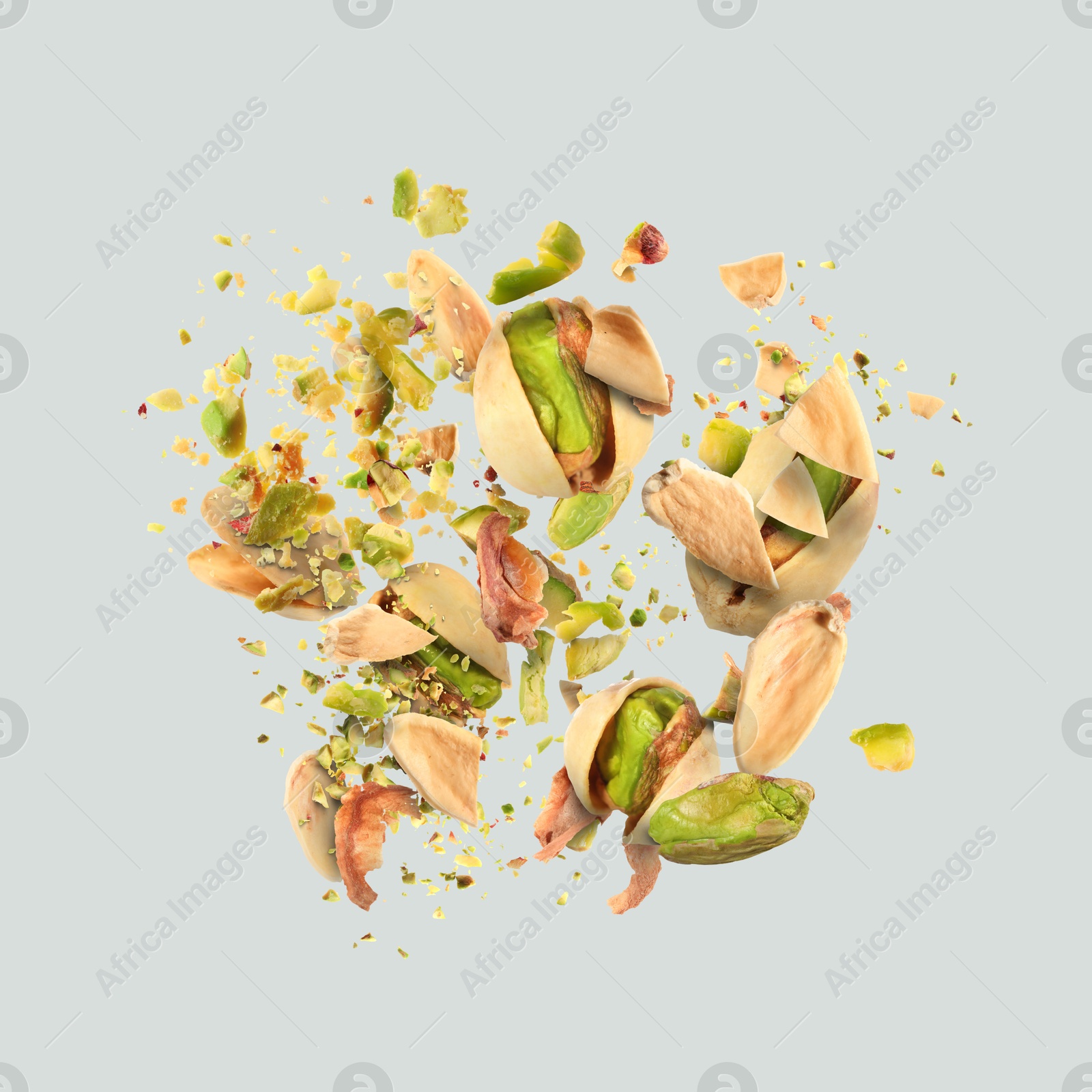 Image of Tasty pistachios with cracked nutshell in air on light grey background