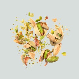 Image of Tasty pistachios with cracked nutshell in air on light grey background