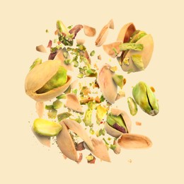 Image of Tasty pistachios with cracked nutshell in air on beige background