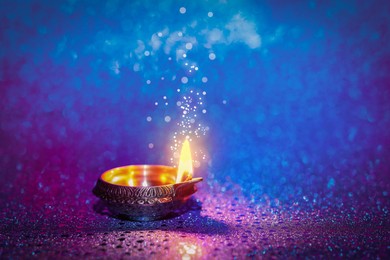 Image of Happy Diwali celebration. Diya lamp burning on color background. Space for text. Bokeh effect