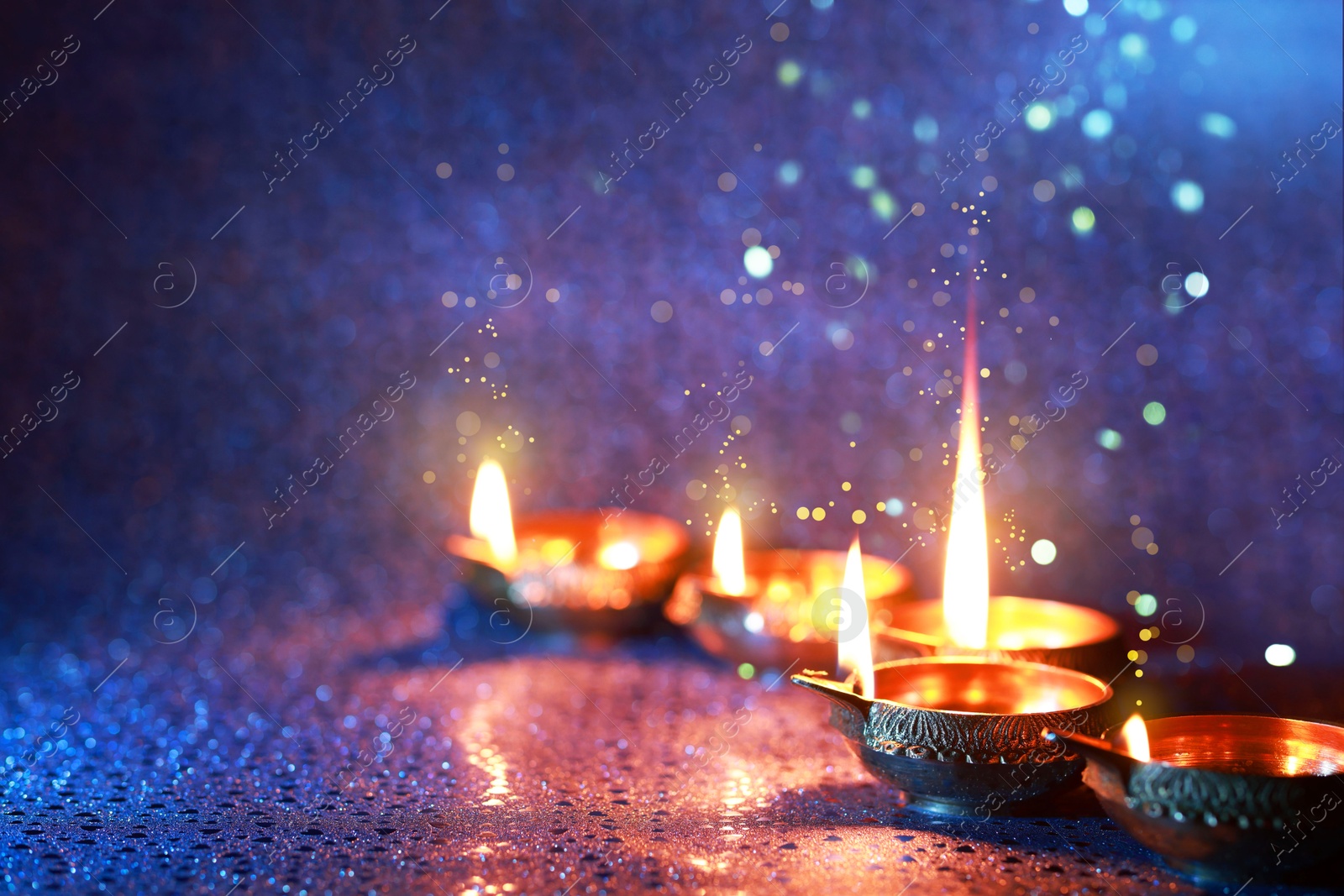 Image of Happy Diwali celebration. Diya lamps burning on color background. Space for text. Bokeh effect