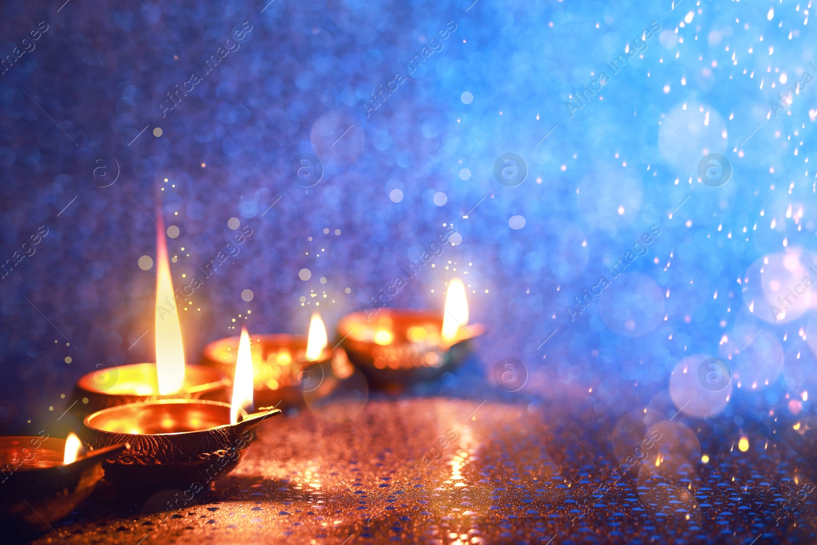 Image of Happy Diwali celebration. Diya lamps burning on color background. Space for text. Bokeh effect