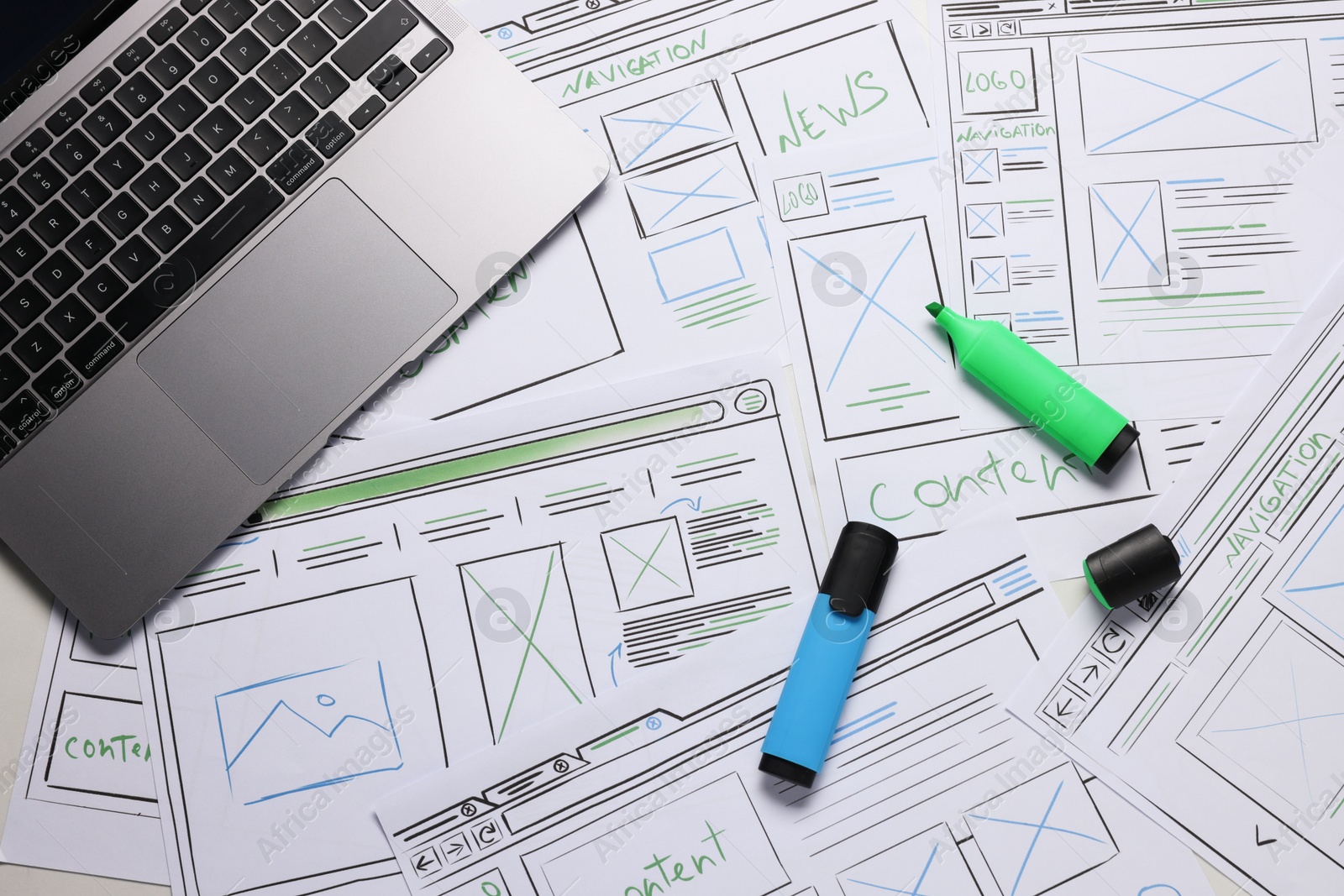 Photo of Developing UI design. Sketches of website wireframes, laptop and felt pens on table, top view