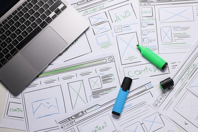 Developing UI design. Sketches of website wireframes, laptop and felt pens on table, top view