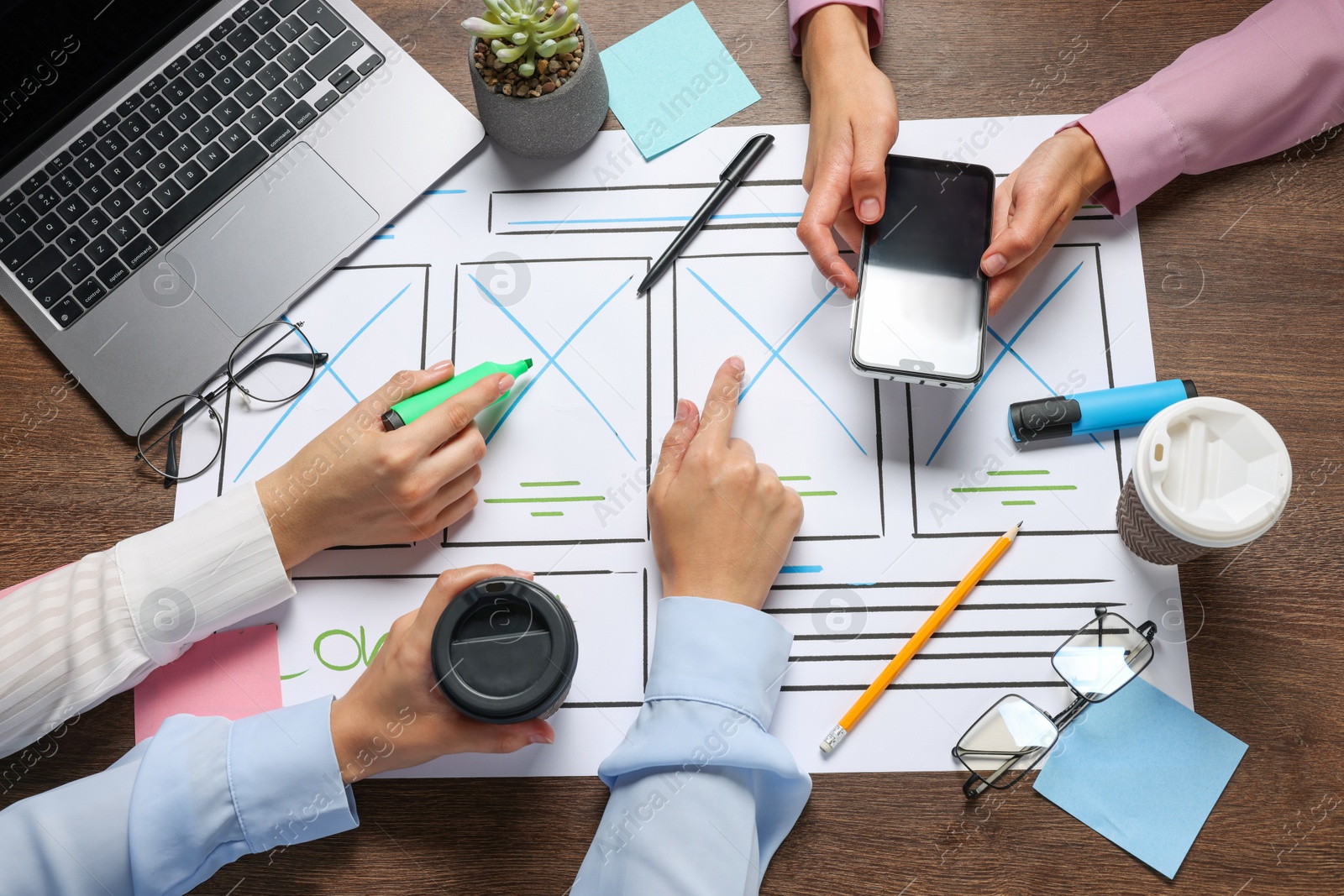 Photo of Developing UI design. Designers creating website wireframe on paper at wooden table, top view