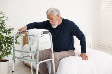 Senior man with walking frame on bed in hospital ward