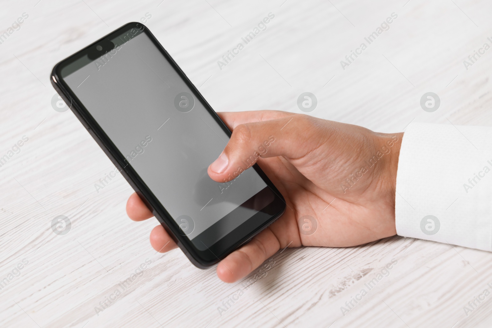 Photo of Man unlocking smartphone with fingerprint scanner at light wooden table, closeup