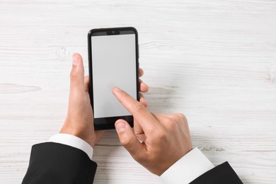 Photo of Man unlocking smartphone with fingerprint scanner at light wooden table, top view