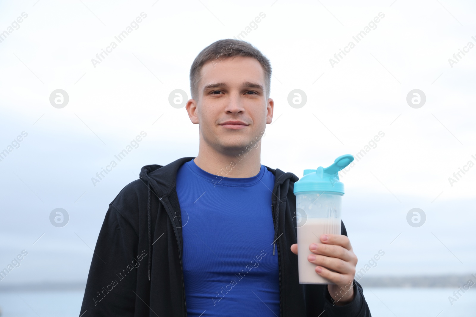 Photo of Athletic man with shaker of protein drink outdoors