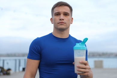 Photo of Athletic man with shaker of protein drink outdoors