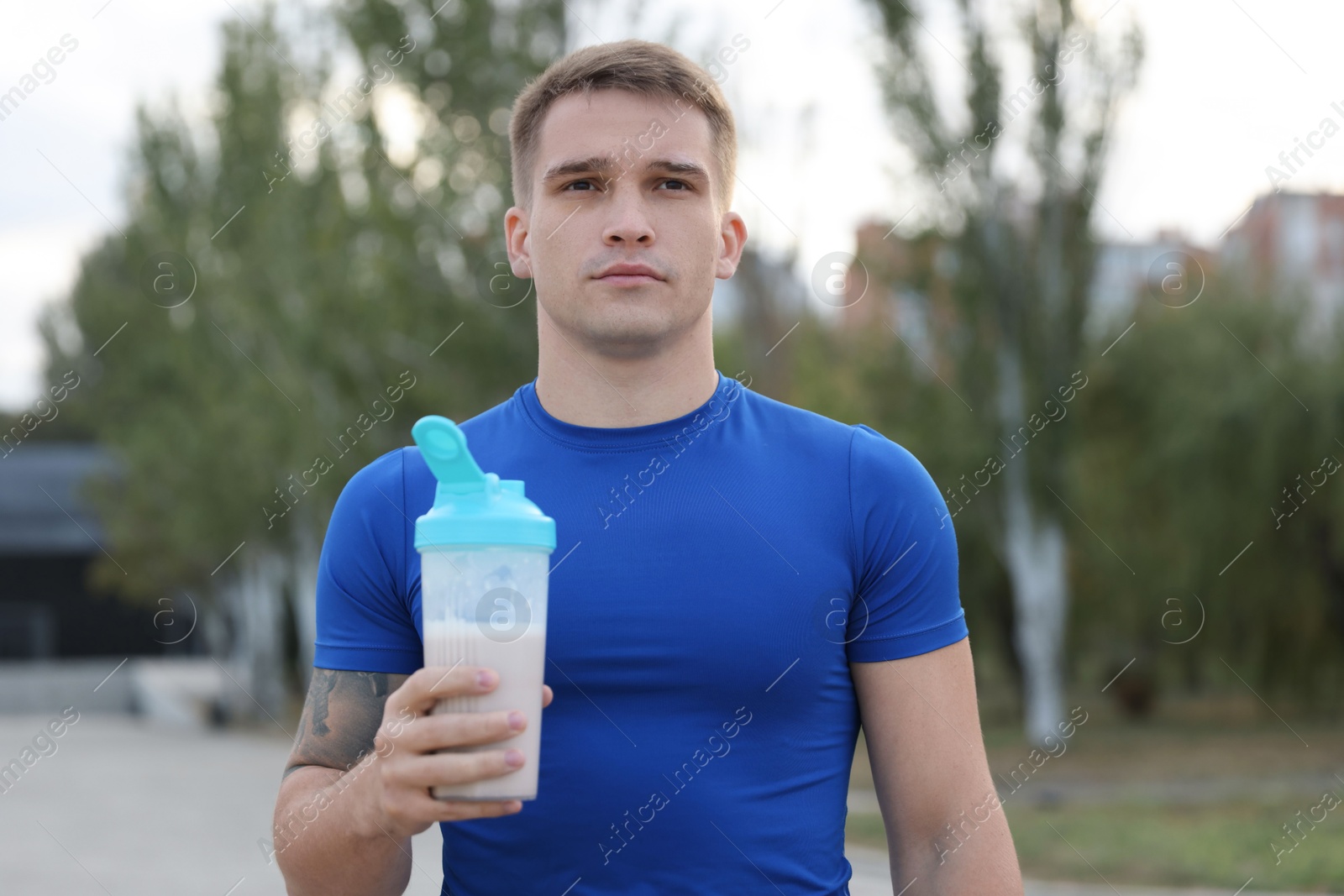 Photo of Athletic man with shaker of protein drink outdoors