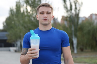 Photo of Athletic man with shaker of protein drink outdoors