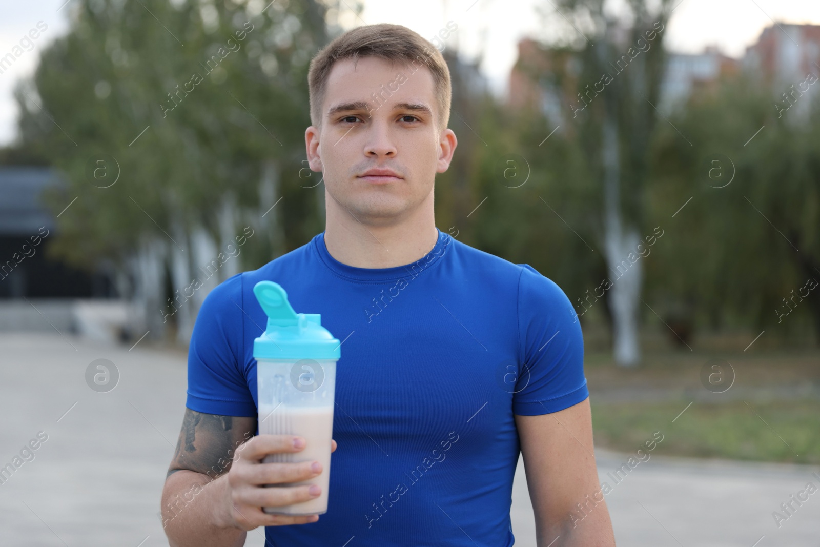 Photo of Athletic man with shaker of protein drink outdoors