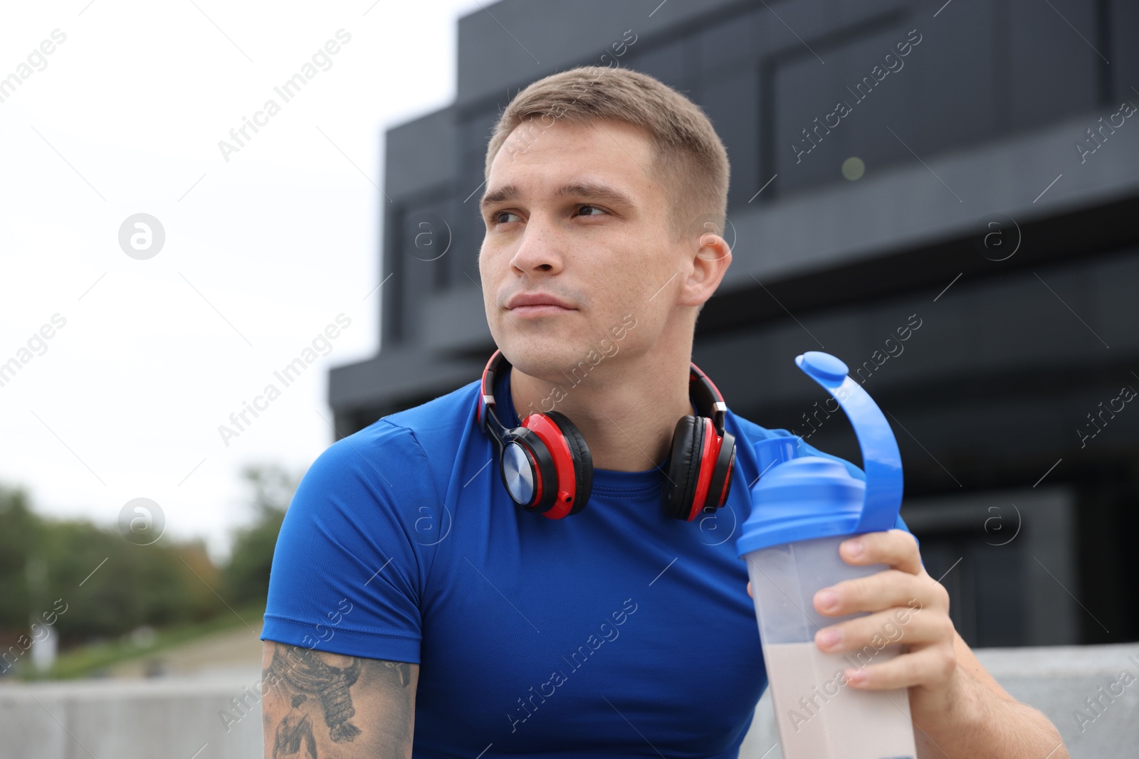 Photo of Athletic man with shaker of protein drink outdoors