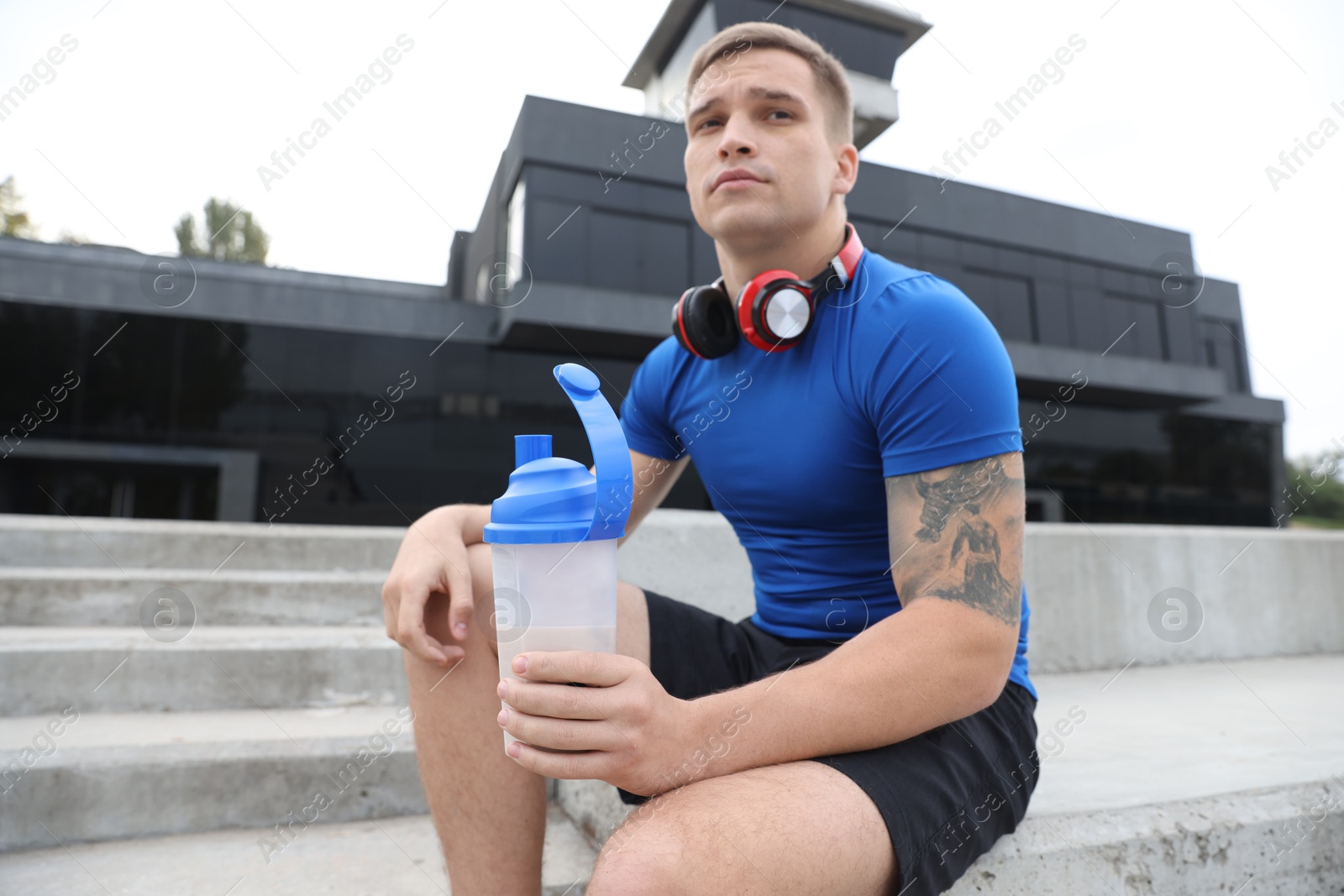 Photo of Athletic man with shaker of protein drink outdoors, low angle view