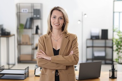 Photo of Portrait of happy businesswoman with crossed arms in office