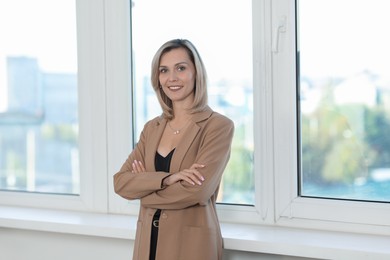 Photo of Portrait of happy businesswoman near window in office