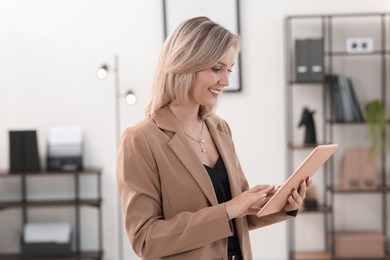 Photo of Portrait of happy businesswoman using tablet in office