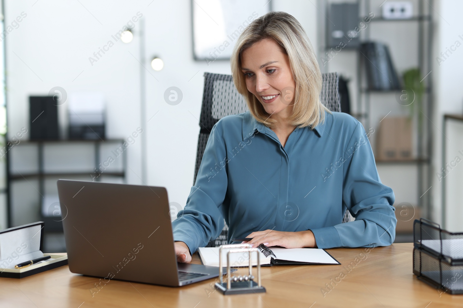 Photo of Happy businesswoman working on laptop at table in office