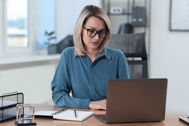 Photo of Businesswoman working on laptop at table in office