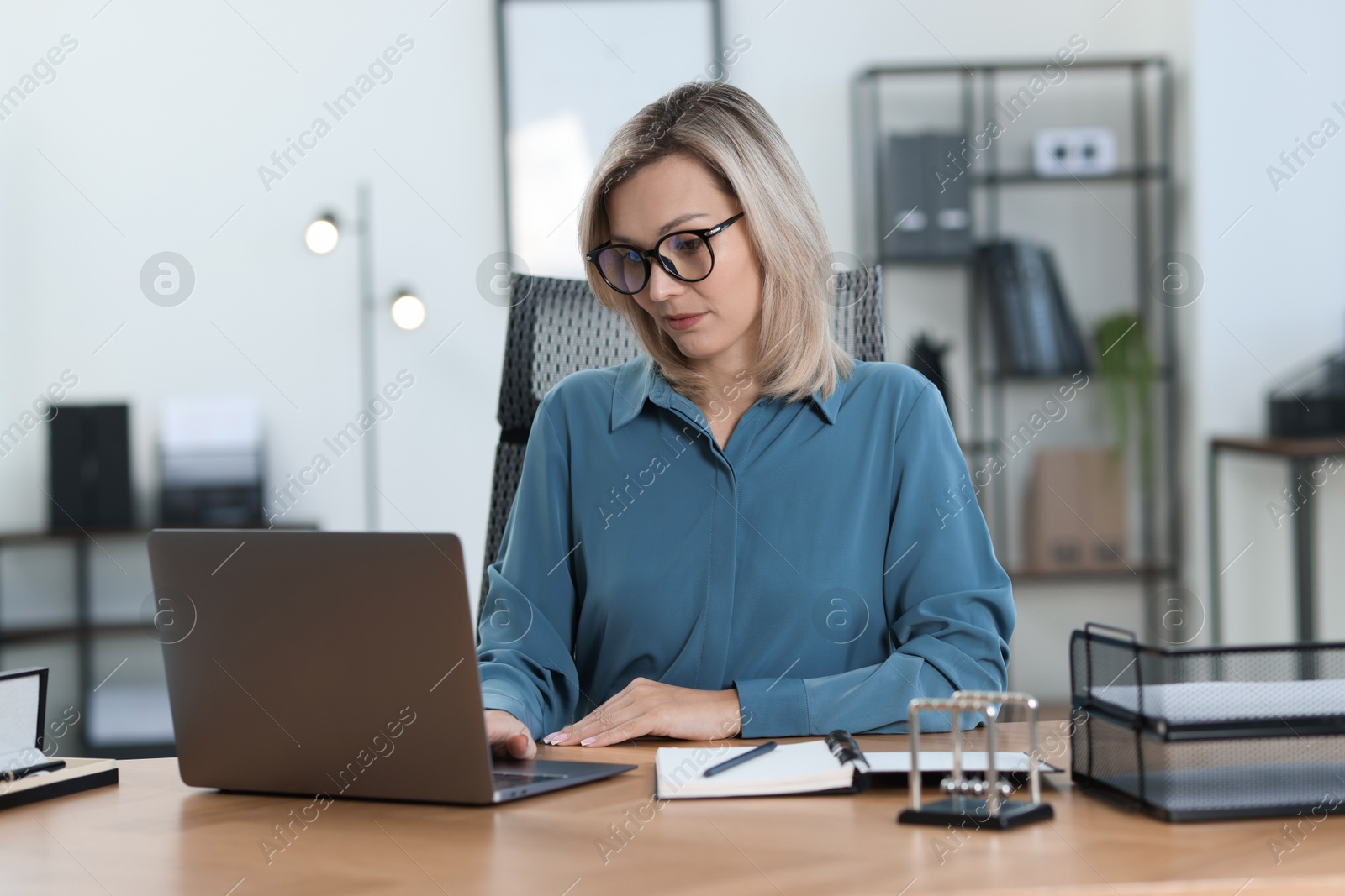 Photo of Businesswoman working on laptop at table in office