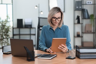 Photo of Businesswoman using tablet at table in office