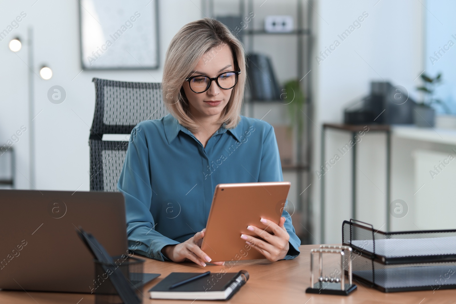 Photo of Businesswoman using tablet at table in office