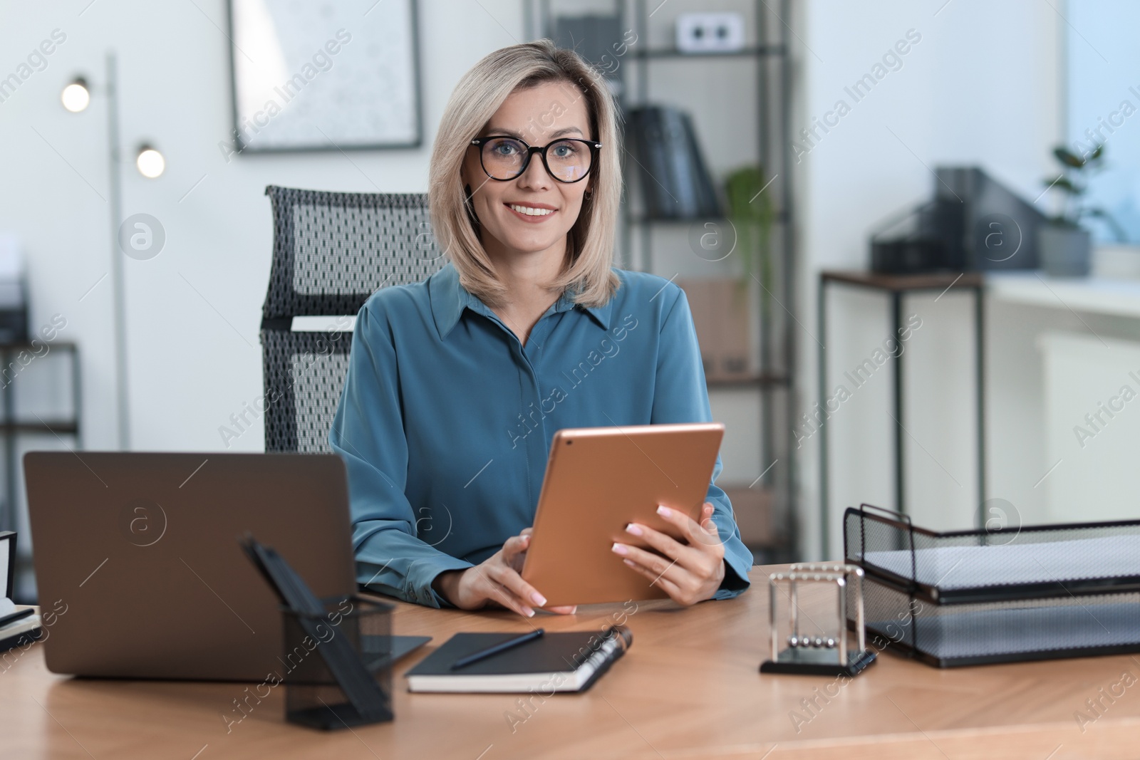 Photo of Businesswoman using tablet at table in office