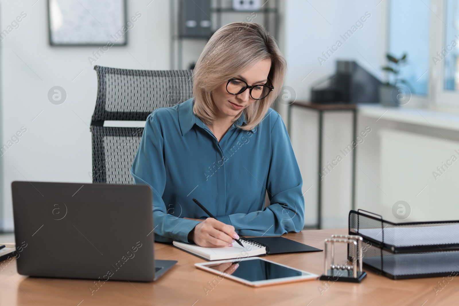 Photo of Businesswoman taking notes at table in office