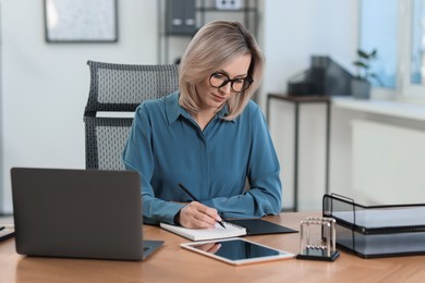 Photo of Businesswoman taking notes at table in office