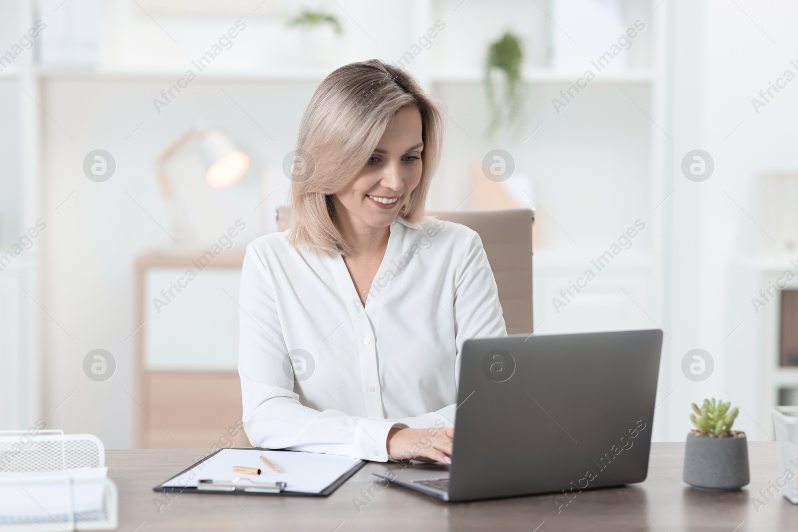 Photo of Businesswoman working on laptop at table in office