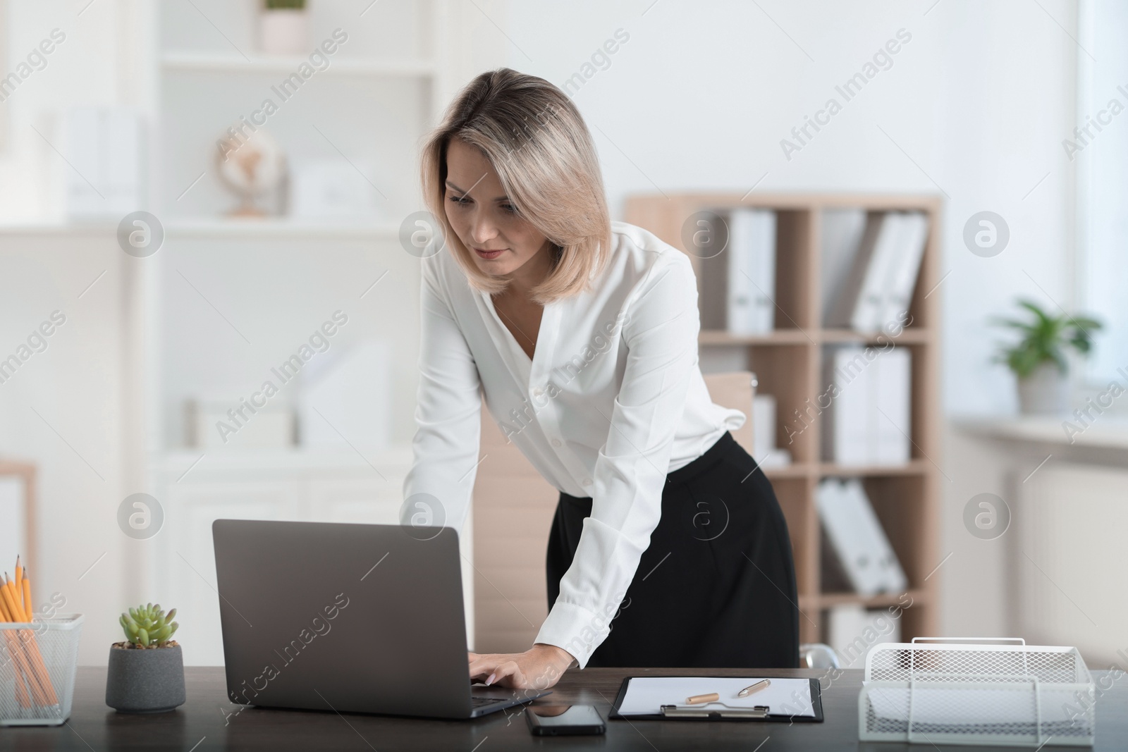 Photo of Businesswoman working on laptop at table in office