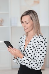 Photo of Portrait of happy businesswoman using smartphone in office