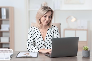 Photo of Businesswoman working on laptop at table in office