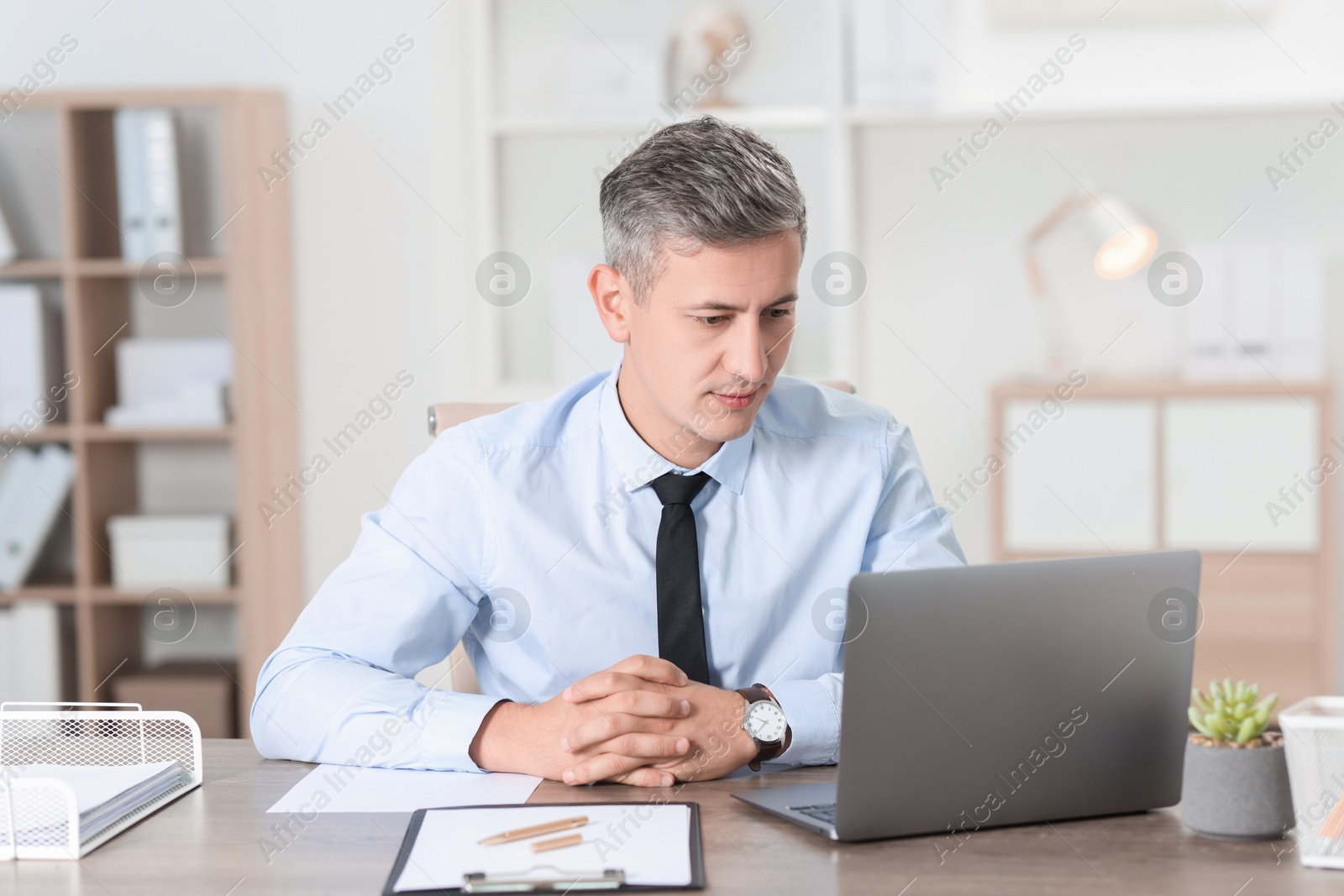 Photo of Businessman working with laptop at table in office