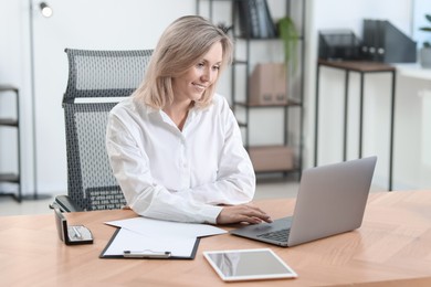 Photo of Businesswoman working on laptop at table in office