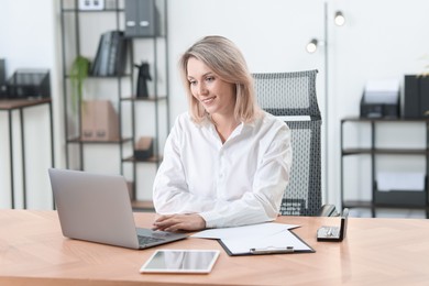 Photo of Businesswoman working on laptop at table in office