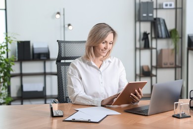 Photo of Businesswoman using tablet at table in office